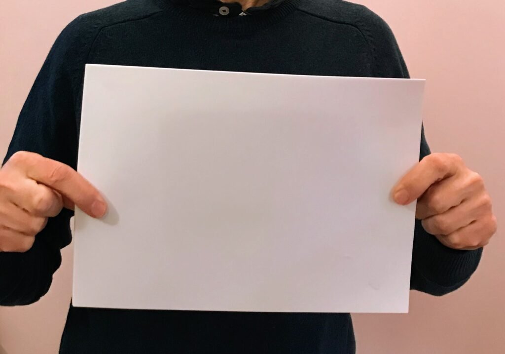 Person holding a sheet of white paper to show paper size